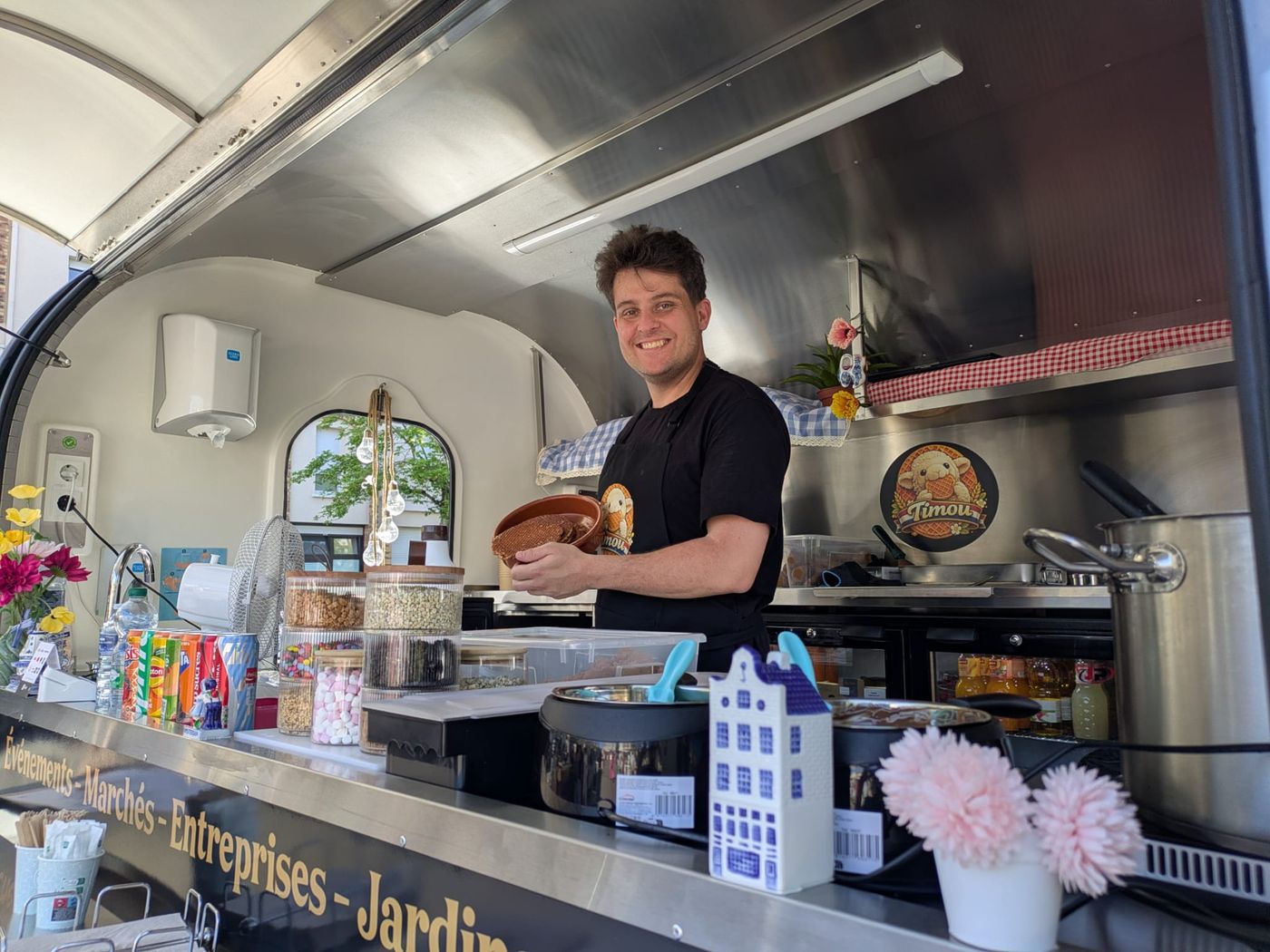 Steven servant une stroopwafel garnie de caramel depuis le comptoir du food truck TIMOU
