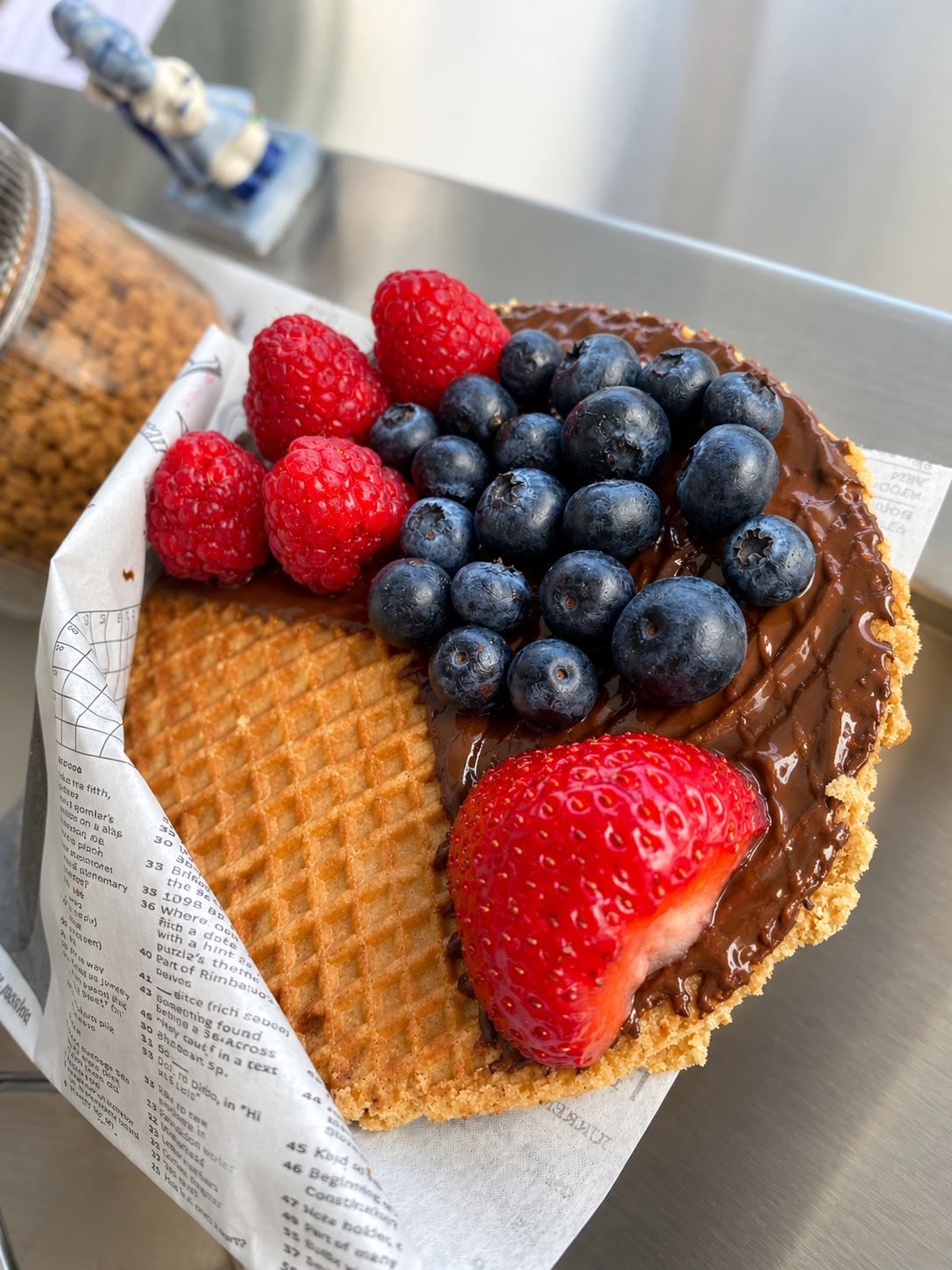 Stroopwafel garnie de chocolat au lait, framboises, myrtilles et fraise fraîche